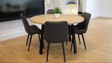 Round wooden table with four black chairs in a room with a TV and shelves.