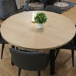 Round wooden table with four black chairs in a classroom with gray sofa and poufs.