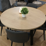Round wooden table with four black chairs in a classroom with gray sofa and poufs.