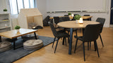 Modern interior with round wooden table and black chairs in a classroom with large windows.