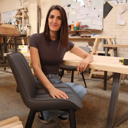 Person sitting with a chair in a workshop with tools and materials around